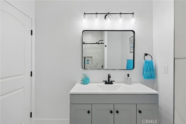bathroom with tiled shower and vanity