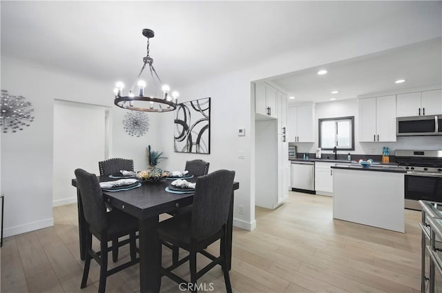dining space with recessed lighting, baseboards, an inviting chandelier, and light wood-type flooring
