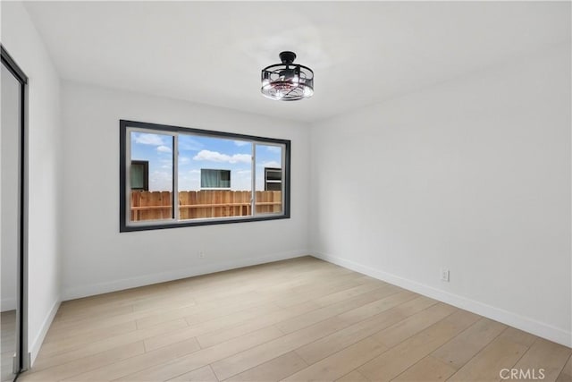 spare room featuring baseboards and light wood-style flooring
