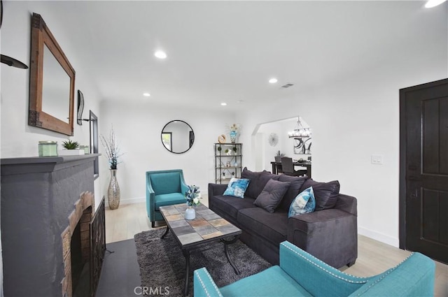 living area with recessed lighting, light wood-style flooring, a fireplace, and an inviting chandelier