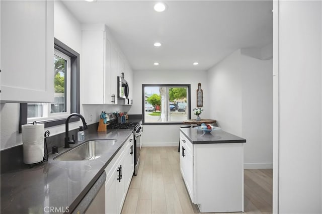 kitchen featuring a sink, white cabinets, light wood-style floors, stainless steel appliances, and recessed lighting