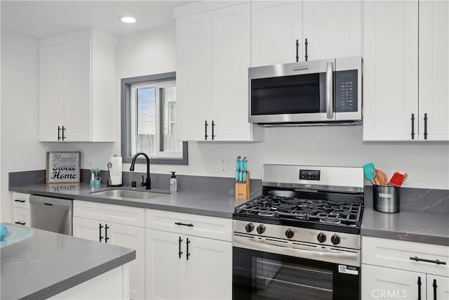 kitchen featuring white cabinetry, dark countertops, appliances with stainless steel finishes, and a sink