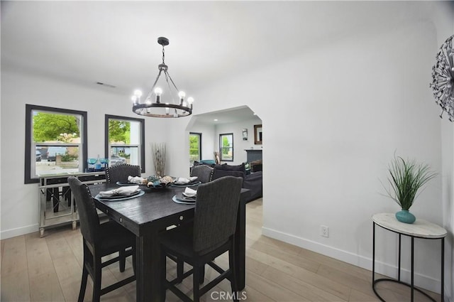 dining room with baseboards, visible vents, light wood finished floors, and a chandelier