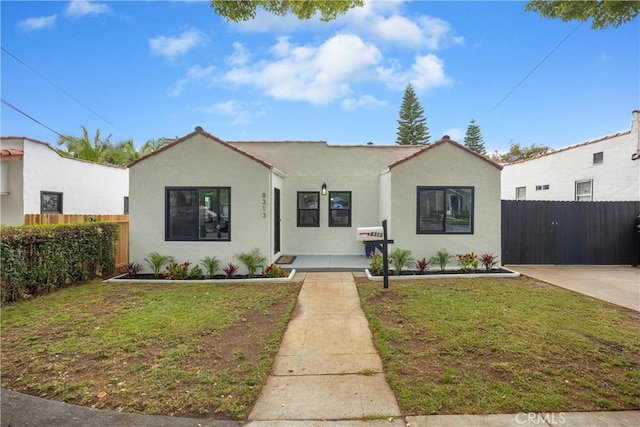 view of front of property featuring fence, stucco siding, and a front yard