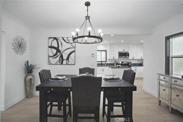 dining space with light wood-style floors, baseboards, plenty of natural light, and a notable chandelier