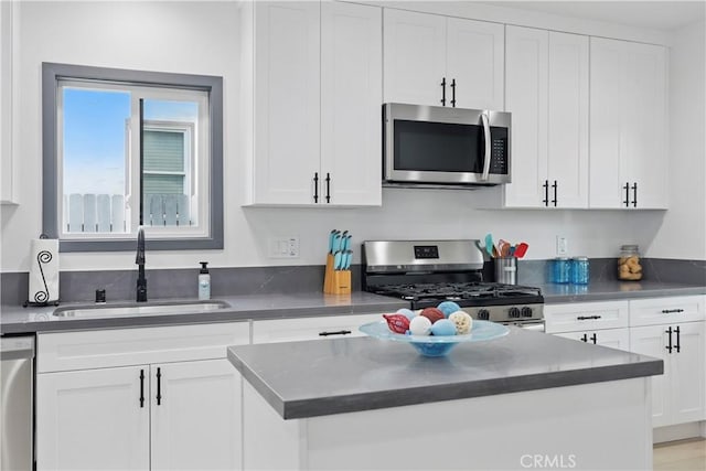 kitchen featuring a sink, appliances with stainless steel finishes, white cabinets, and dark countertops