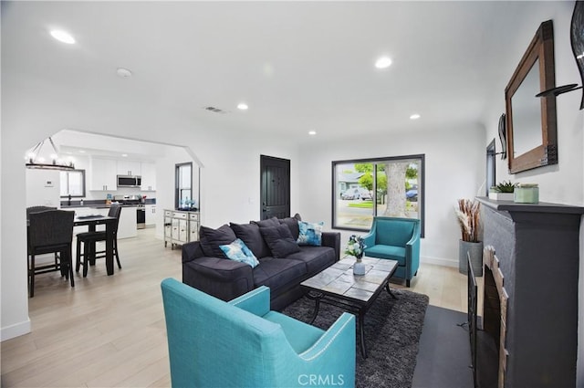living room with recessed lighting, baseboards, visible vents, and light wood finished floors