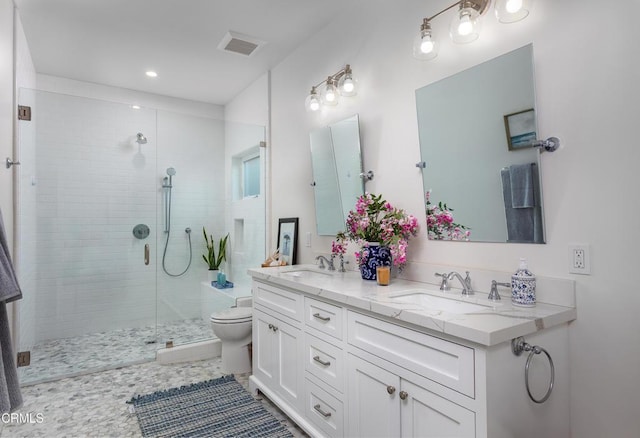bathroom featuring double vanity, toilet, a sink, and a stall shower