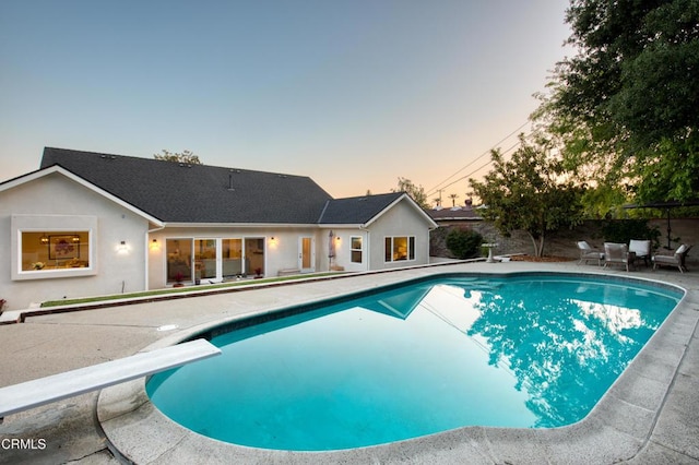 pool at dusk featuring a fenced in pool and a patio
