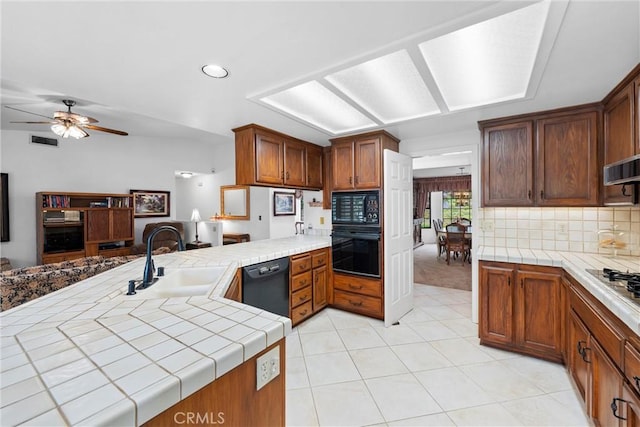 kitchen featuring light tile patterned flooring, a sink, tile countertops, visible vents, and black appliances