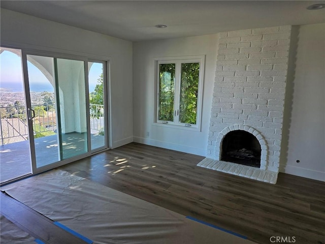 unfurnished living room featuring baseboards, wood finished floors, and a fireplace