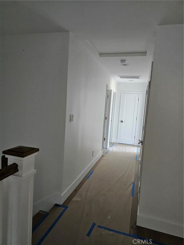 hallway featuring baseboards and an upstairs landing