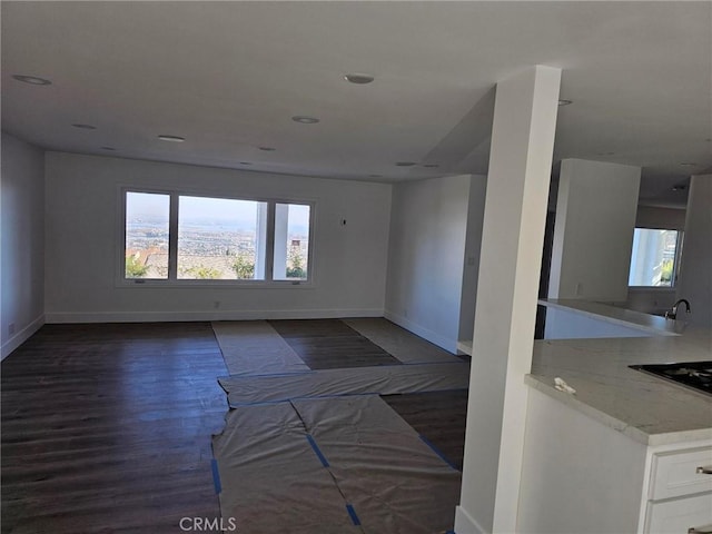 unfurnished living room with recessed lighting, baseboards, and dark wood-style floors