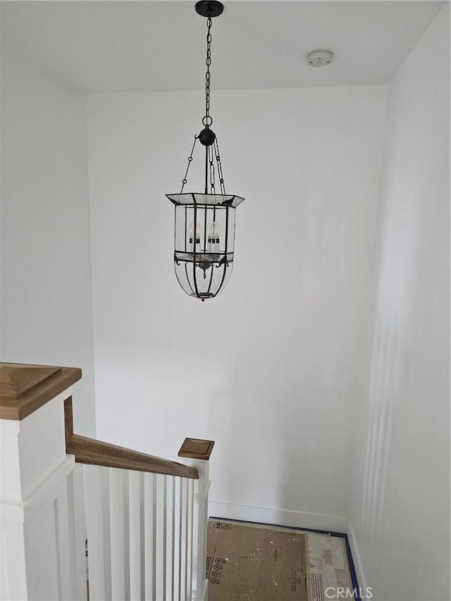 stairs featuring baseboards and an inviting chandelier