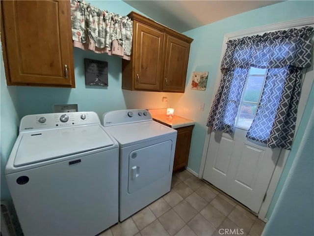 clothes washing area with cabinet space, washing machine and dryer, and light tile patterned flooring
