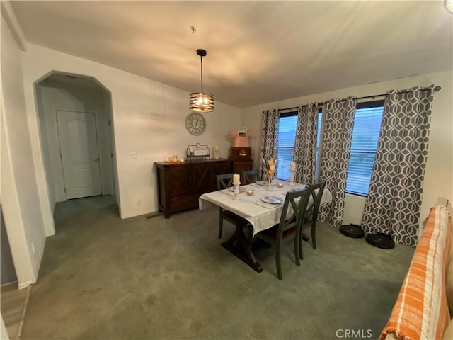 carpeted dining room featuring arched walkways