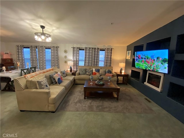 carpeted living room featuring an inviting chandelier, plenty of natural light, and visible vents