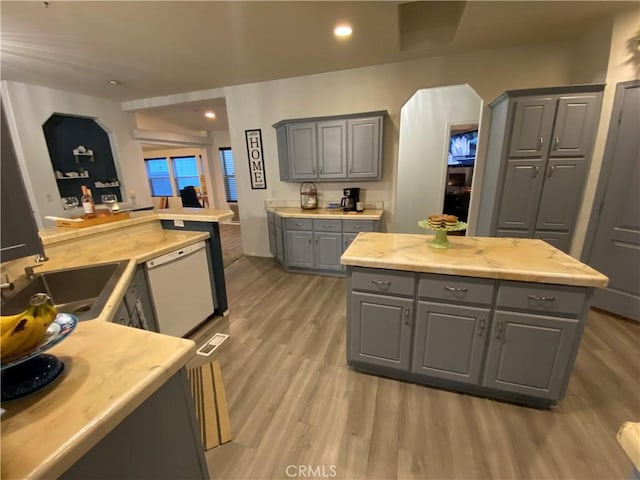 kitchen featuring light countertops, a sink, gray cabinets, and dishwasher