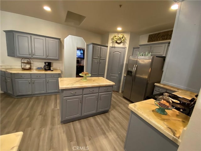 kitchen featuring light wood finished floors, stainless steel fridge with ice dispenser, gray cabinets, and recessed lighting