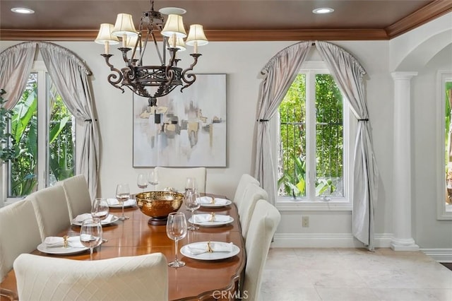 dining area featuring ornate columns, a chandelier, arched walkways, baseboards, and crown molding