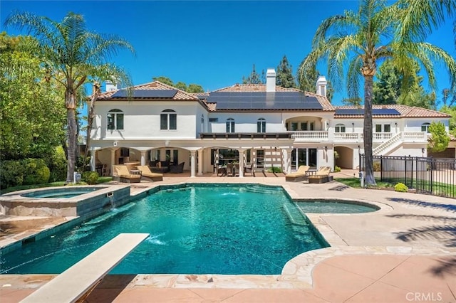 rear view of house featuring outdoor lounge area, solar panels, a patio, and a pool with connected hot tub