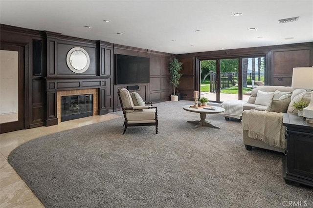 living area with a decorative wall, a tiled fireplace, and light carpet
