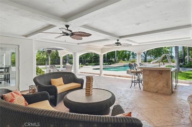 view of patio / terrace featuring a ceiling fan, an outdoor bar, and an outdoor pool