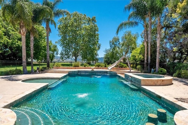 view of pool with a water slide, a pool with connected hot tub, and a patio area
