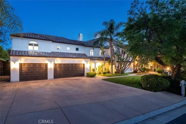 mediterranean / spanish-style house featuring driveway, an attached garage, stucco siding, a chimney, and a tiled roof