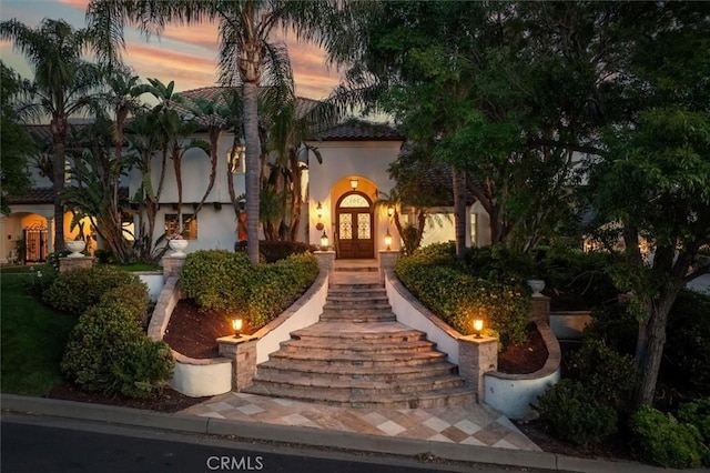 mediterranean / spanish-style home featuring french doors, stucco siding, and a tiled roof