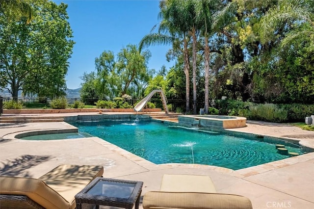 view of swimming pool with a water slide, a patio area, a pool with connected hot tub, and a mountain view