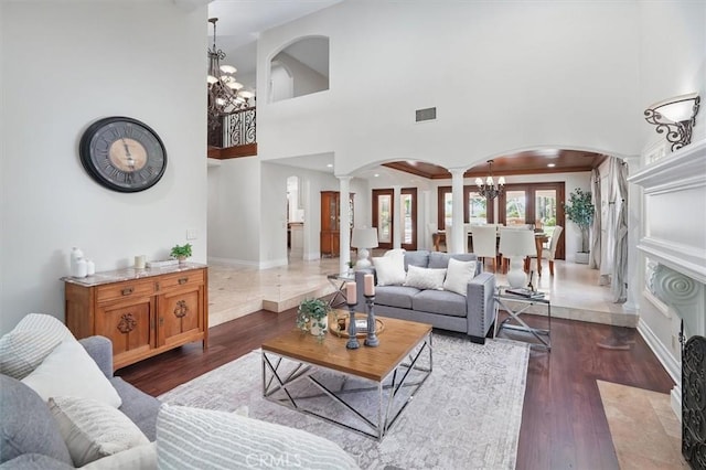 living area with ornate columns, arched walkways, a chandelier, dark wood-style flooring, and recessed lighting