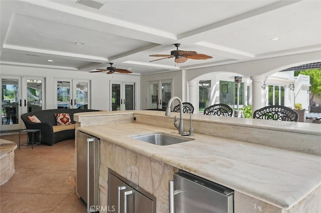 kitchen with a sink, coffered ceiling, arched walkways, healthy amount of natural light, and open floor plan