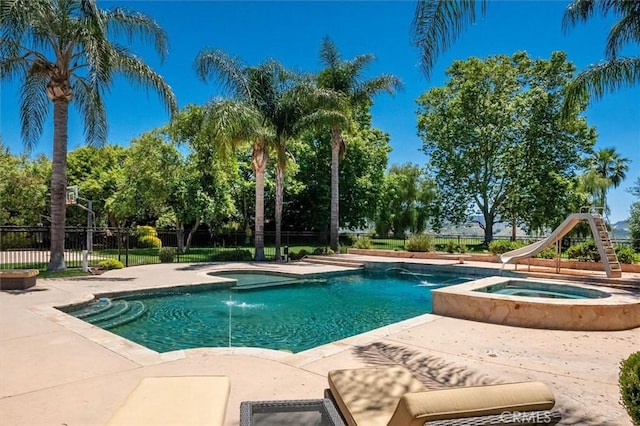view of swimming pool with a patio area, a pool with connected hot tub, and a water slide