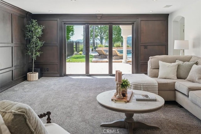 carpeted living area featuring a decorative wall and recessed lighting