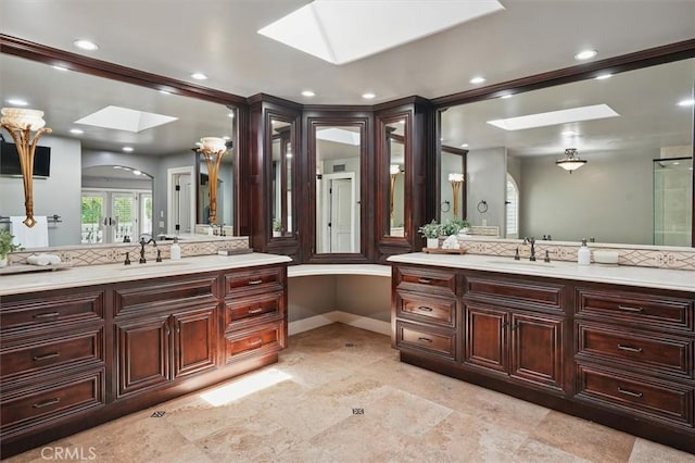 full bath with a skylight, two vanities, recessed lighting, and baseboards