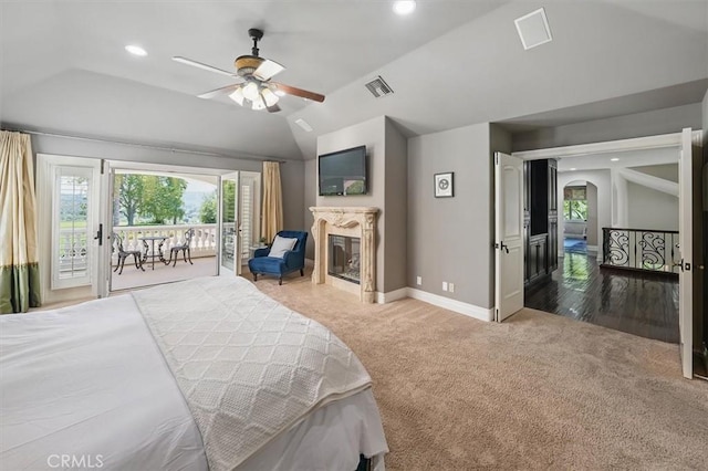 bedroom with carpet flooring, access to exterior, a premium fireplace, vaulted ceiling, and multiple windows
