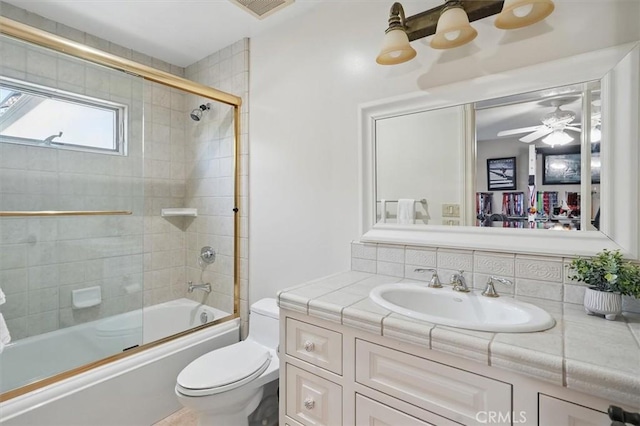full bathroom featuring toilet, vanity, combined bath / shower with glass door, decorative backsplash, and a ceiling fan