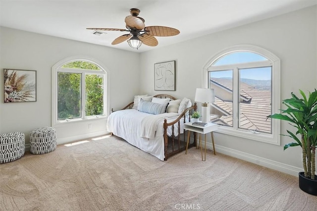 carpeted bedroom featuring multiple windows, baseboards, and ceiling fan