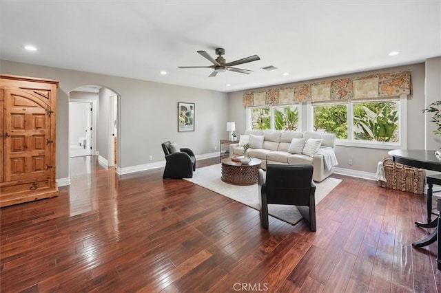 living area featuring arched walkways, a ceiling fan, baseboards, dark wood-style flooring, and recessed lighting