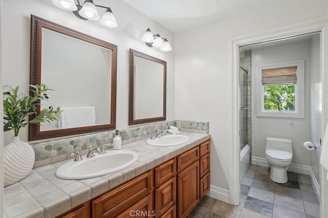 bathroom featuring toilet, double vanity, and baseboards