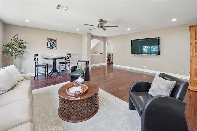 living room featuring arched walkways, wood finished floors, a ceiling fan, recessed lighting, and baseboards