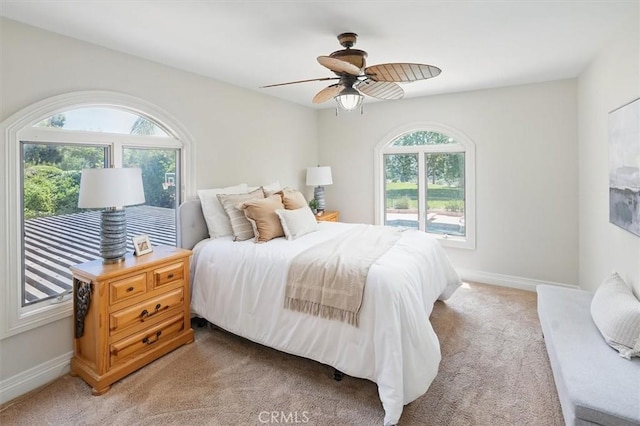 bedroom with light colored carpet, baseboards, and ceiling fan