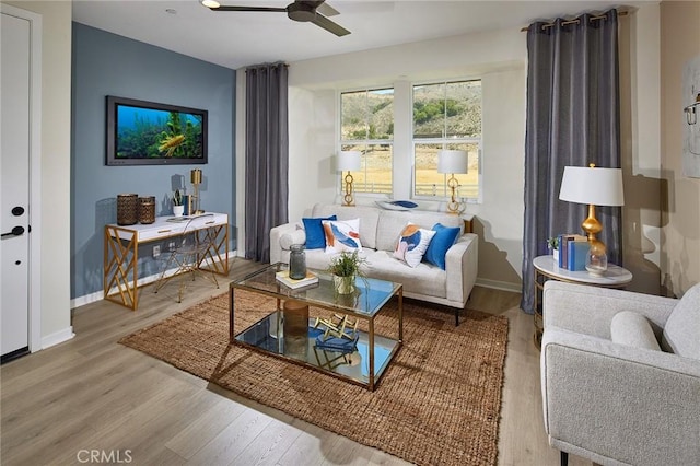 living room featuring baseboards, a ceiling fan, and wood finished floors