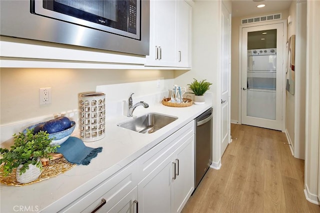 bar featuring wet bar, visible vents, appliances with stainless steel finishes, a sink, and light wood-style flooring
