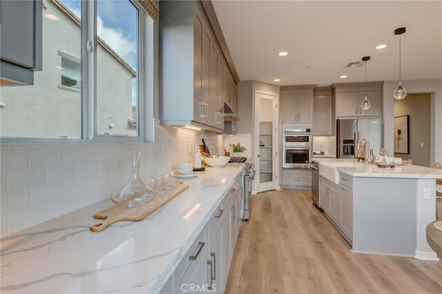 30973 Avenida Ramblas, Highland, CA 92346 - kitchen with appliances with stainless steel finishes, light wood-style flooring, decorative backsplash, visible vents, and pendant lighting