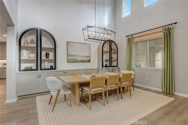 30973 Avenida Ramblas, Highland, CA 92346 - dining area featuring a towering ceiling, baseboards, a chandelier, and light wood-style floors