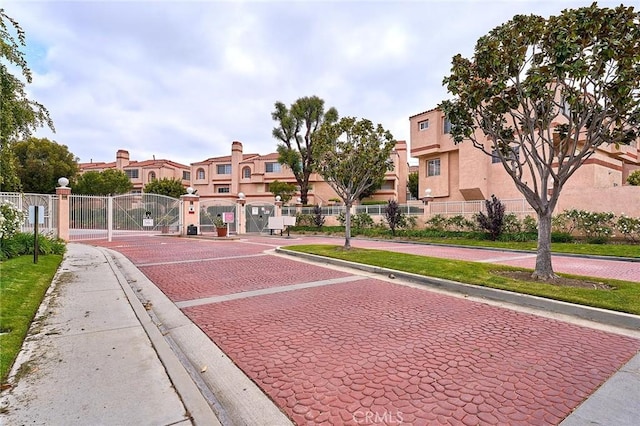 view of property's community with a gate, uncovered parking, fence, and a residential view