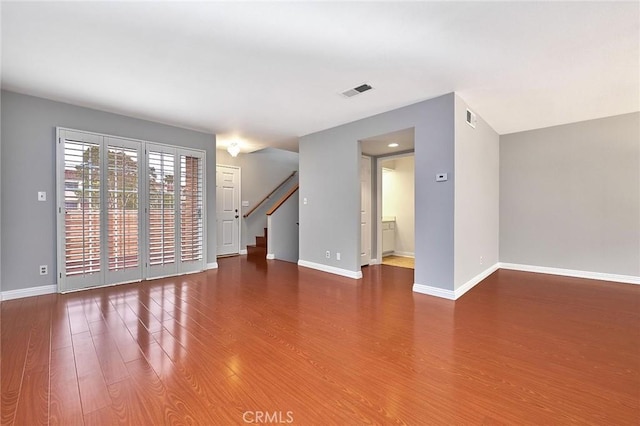 unfurnished living room with stairs, baseboards, visible vents, and wood finished floors
