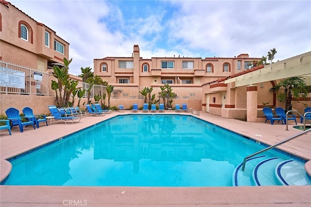 community pool with fence and a patio area